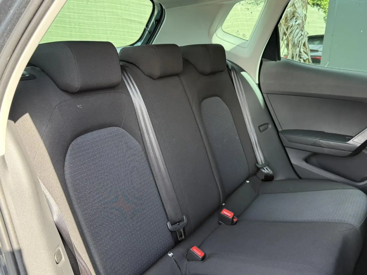 Vue intérieure de la banquette arrière noire du SEAT Arona 2025, avec ceintures de sécurité et appuie-têtes visibles.