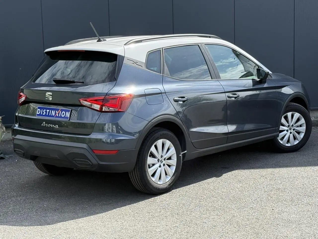 Vue 3/4 arrière droite du SEAT Arona gris magnétique avec toit blanc et jantes alliage 16 pouces sur fond urbain.