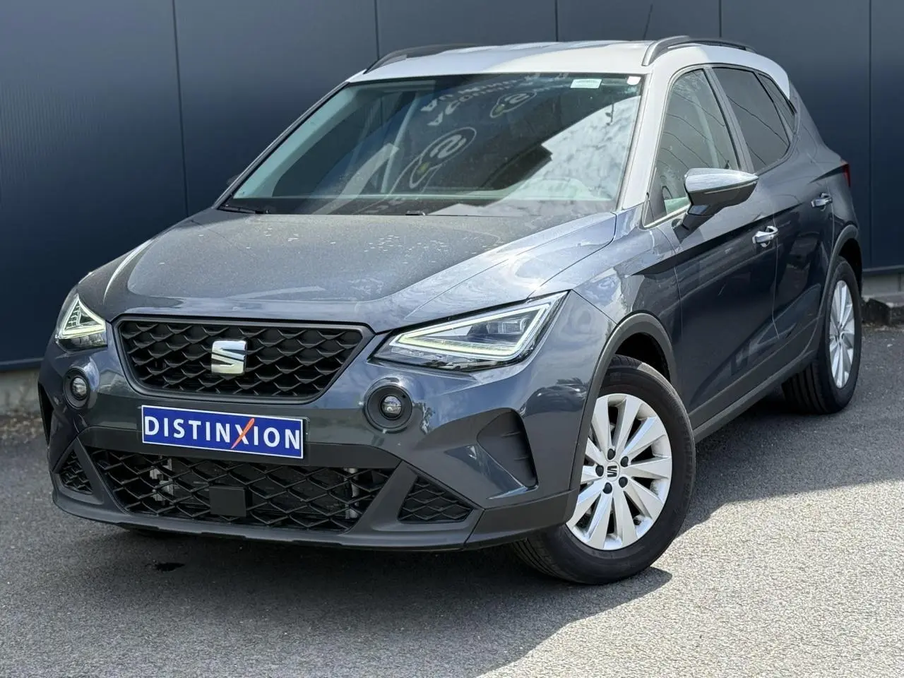 Vue 3/4 avant droite d'un SEAT Arona 2025 gris magnétique avec toit blanc et jantes alliage 16 pouces.