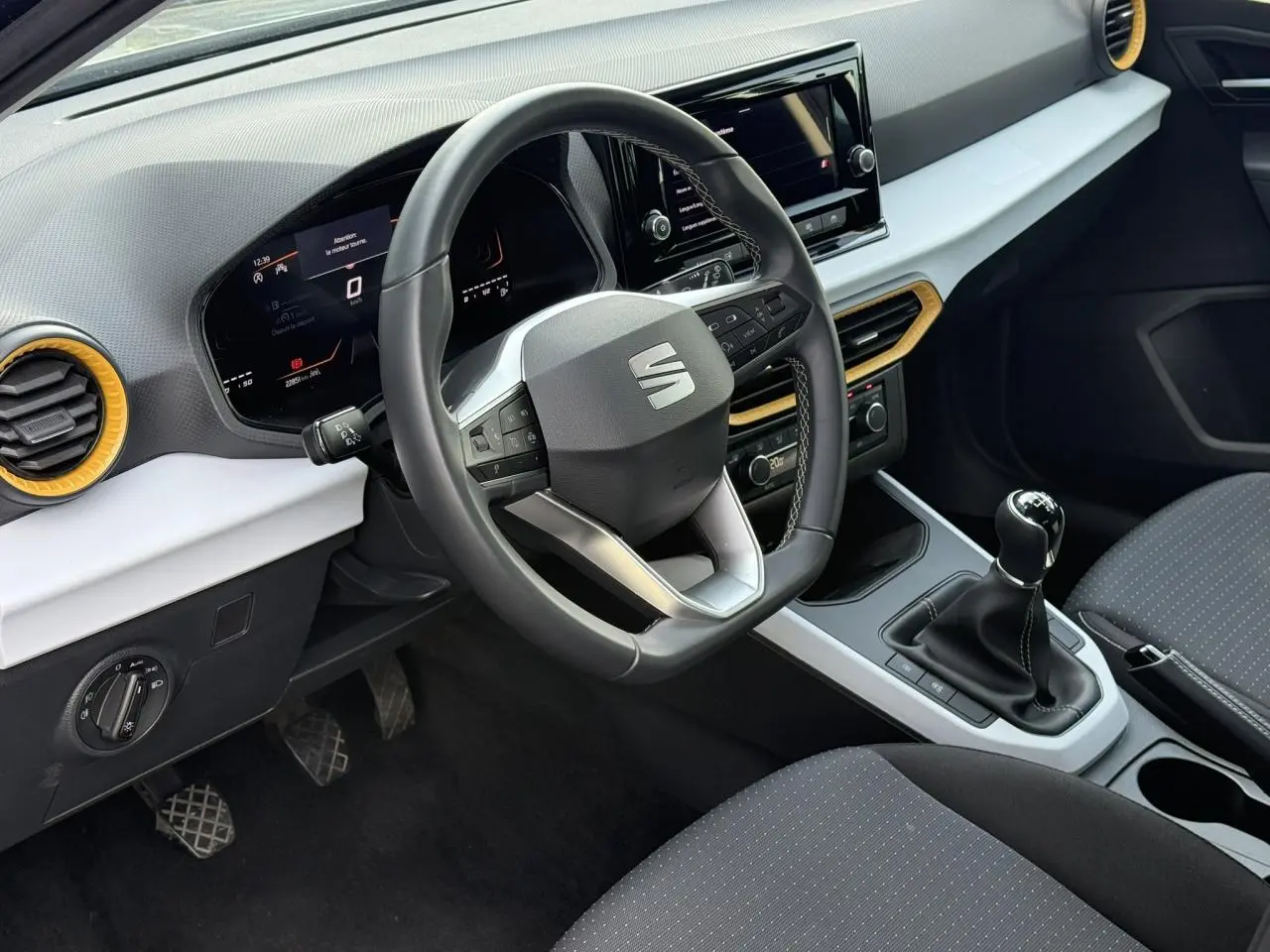 Vue intérieure du poste de conduite du SEAT Arona TSI 115 Style 2025, volant multifonction et levier de vitesse manuel visibles.