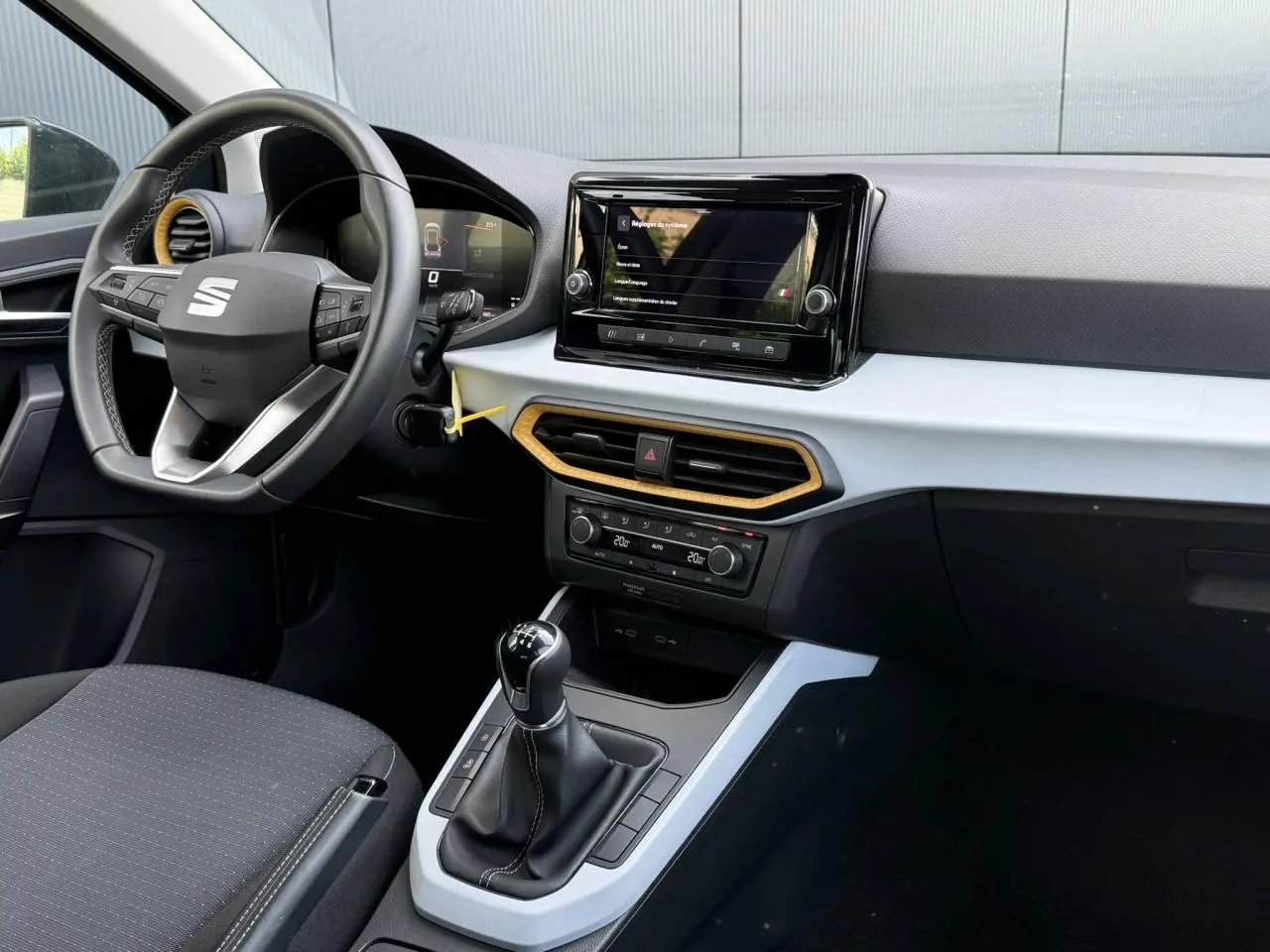 Vue intérieure côté conducteur du tableau de bord gris clair et noir du SEAT Arona TSI 115 avec volant multifonction et écran tactile central.