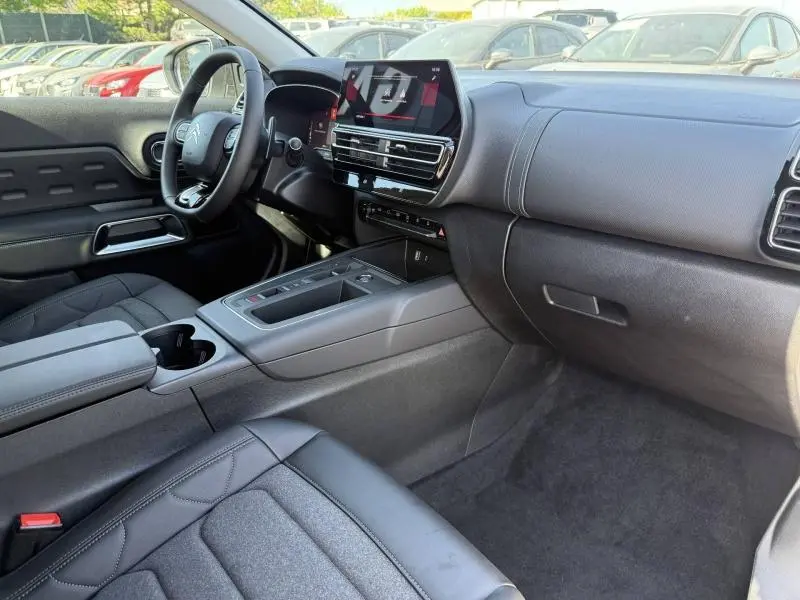 Intérieur avant droit du Citroën C5 Aircross 2025 hybride blanc, avec tableau de bord moderne et écran tactile central.