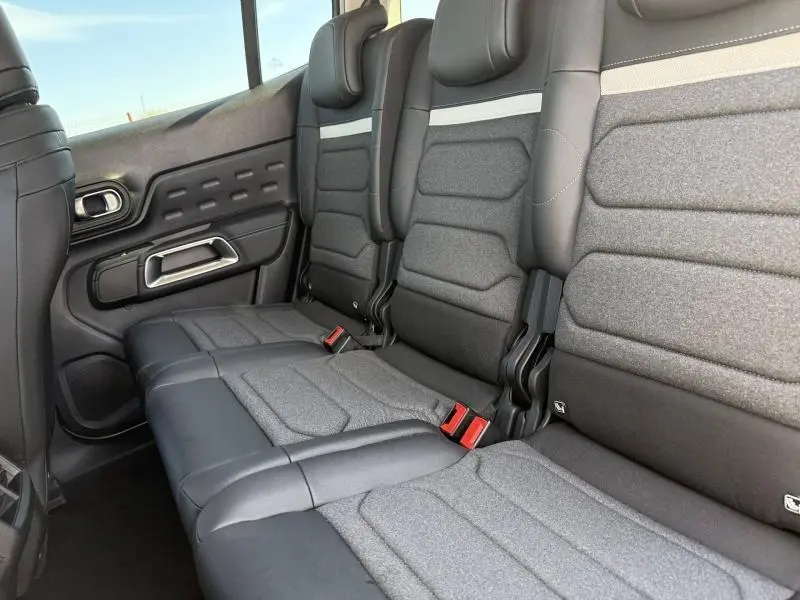 Vue intérieure des sièges arrière en tissu gris et cuir noir du Citroën C5 Aircross 2025, côté gauche avec ceinture rouge visible.