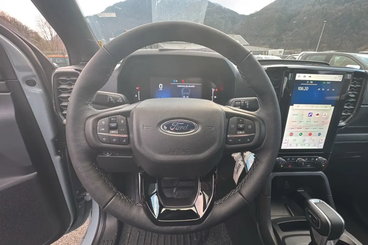 Vue intérieure centrée sur le volant cuir multifonctions et l’écran tactile vertical du Ford Ranger gris commandeur.