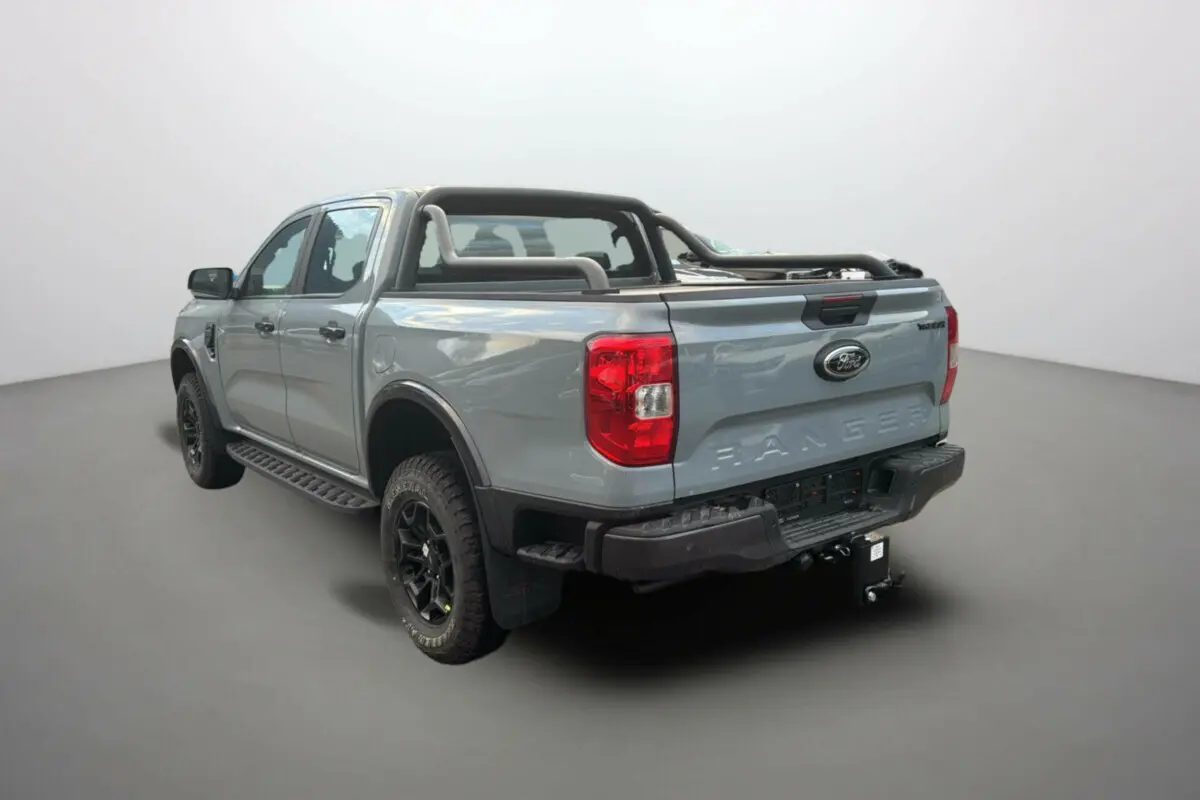 Ford Ranger gris commandeur vu en 3/4 arrière droit avec arceaux noirs et attelage visible.