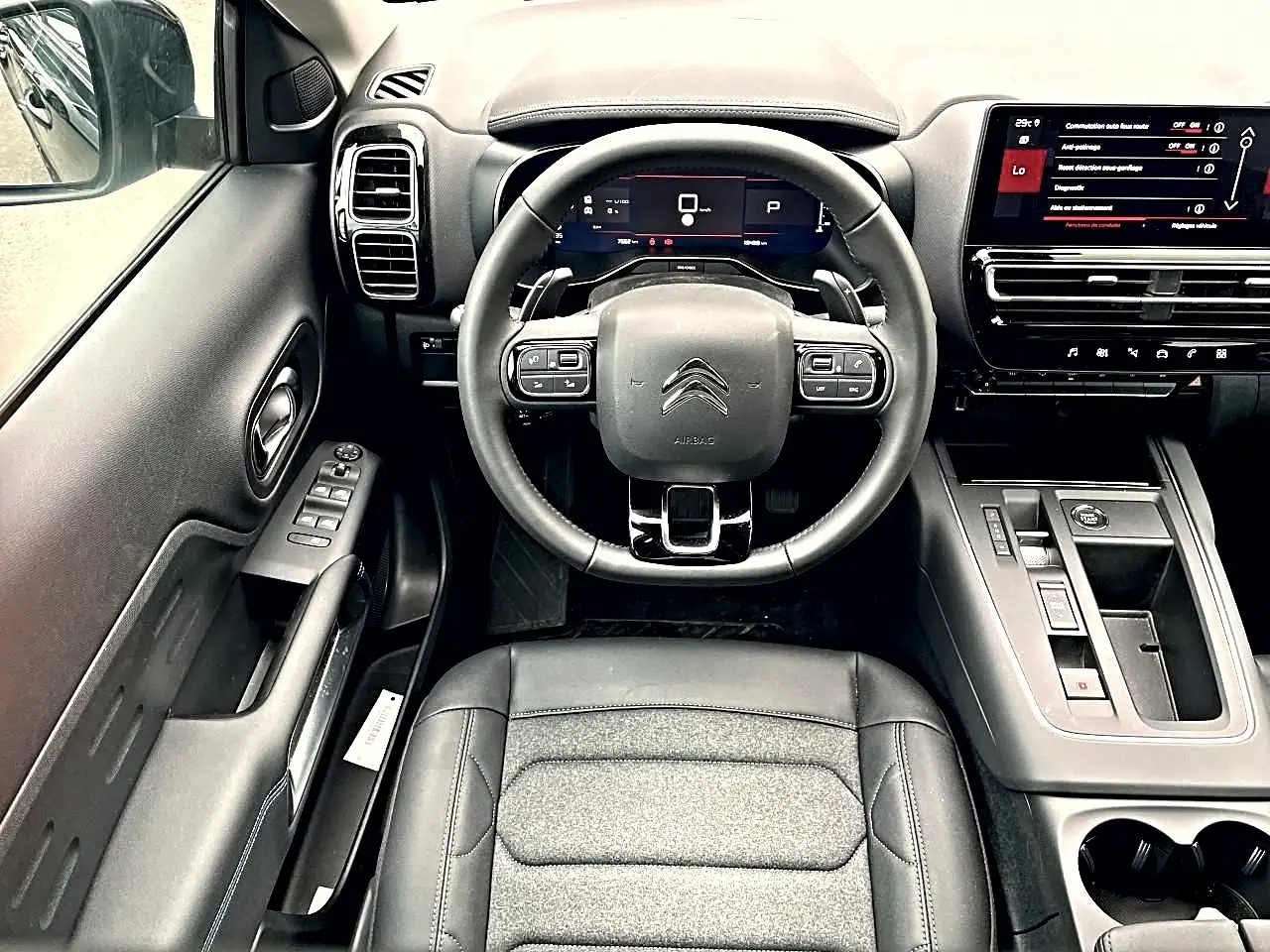 Vue intérieure frontale du poste de conduite noir du Citroën C5 Aircross 2025 avec volant multifonction et écran tactile.