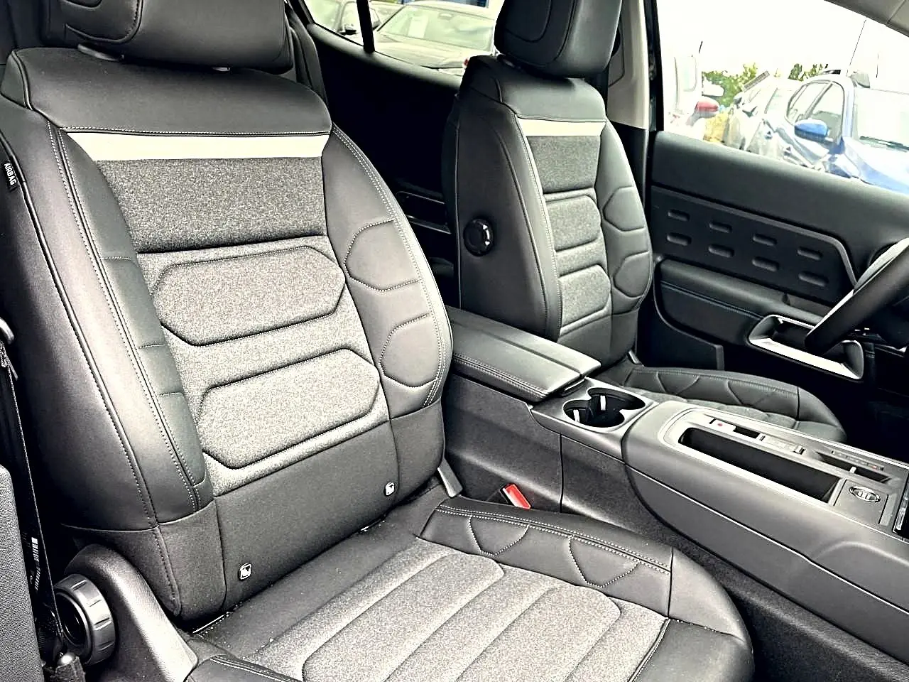 Vue intérieure rapprochée des sièges avant noirs et gris du Citroën C5 Aircross avec accoudoir central et console.