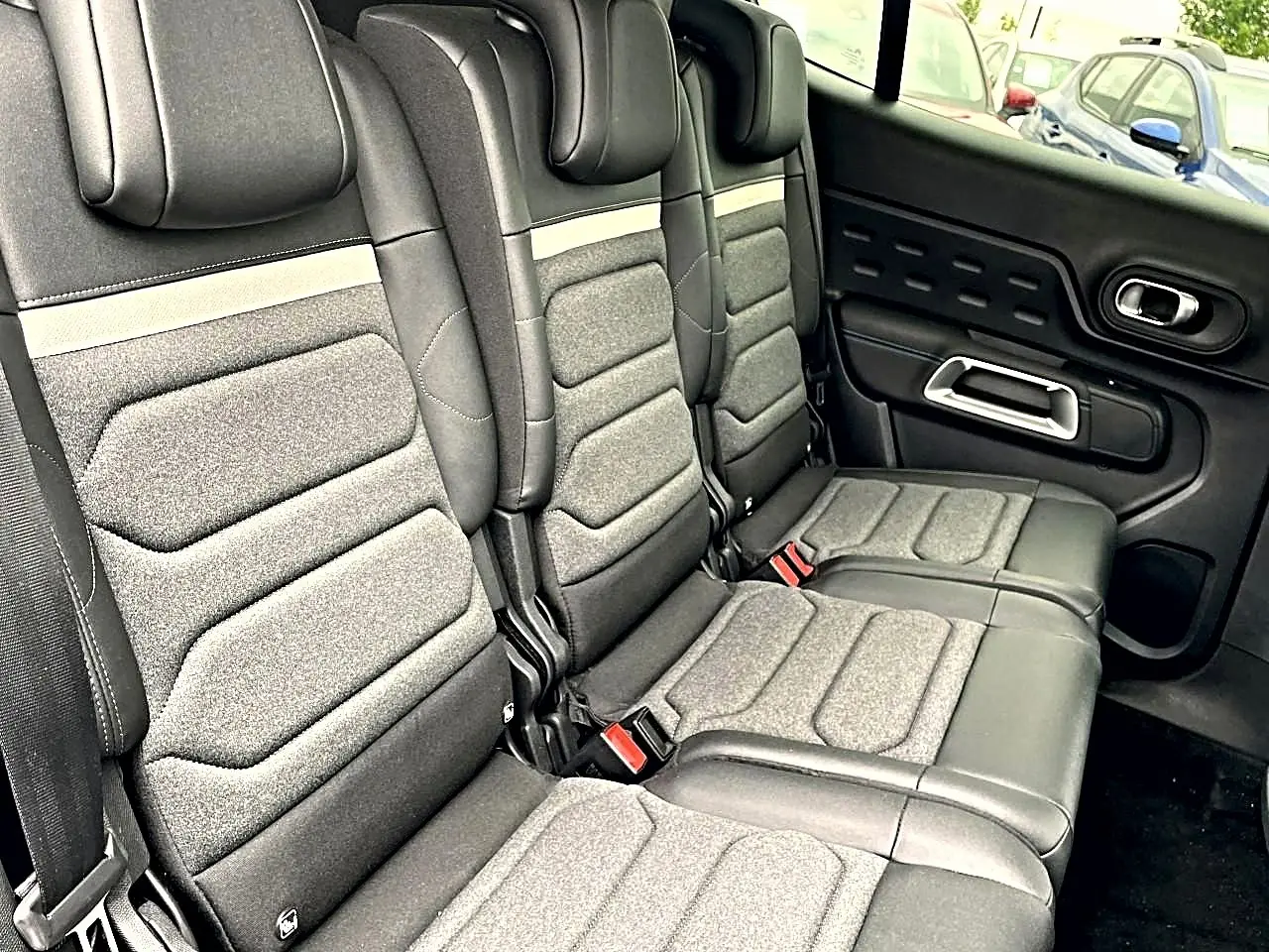 Vue latérale des sièges arrière gris et noirs du Citroën C5 Aircross 2025 avec appuie-têtes et ceintures visibles.