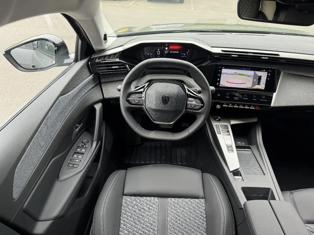Vue intérieure avant de la Peugeot 308 2026, tableau de bord moderne avec écran tactile et volant compact noir.