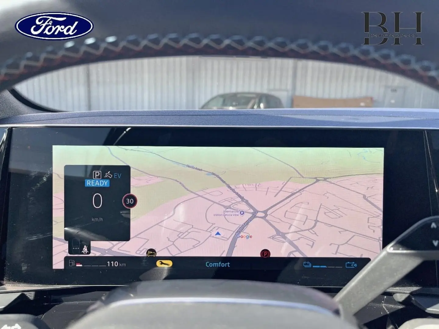 Vue intérieure du tableau de bord du Ford avec écran tactile affichant la navigation GPS et informations de conduite.