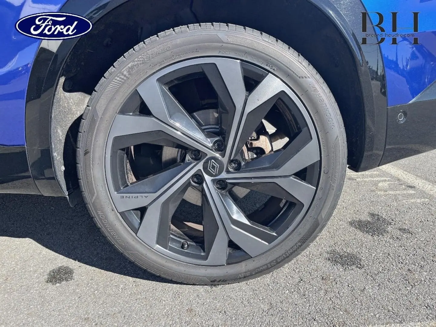 Gros plan sur la roue arrière droite bleu Iron du Renault Austral 1.2 E-Tech avec jante alu noire esprit Alpine.