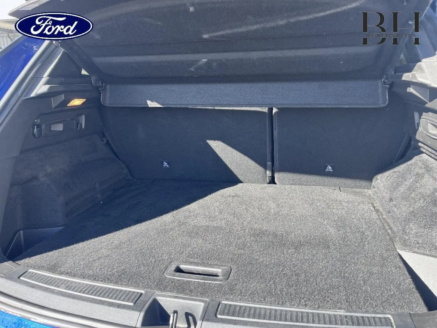 Coffre ouvert vu de l'arrière d'un Renault Austral Bleu Iron, montrant un espace de chargement propre et spacieux.