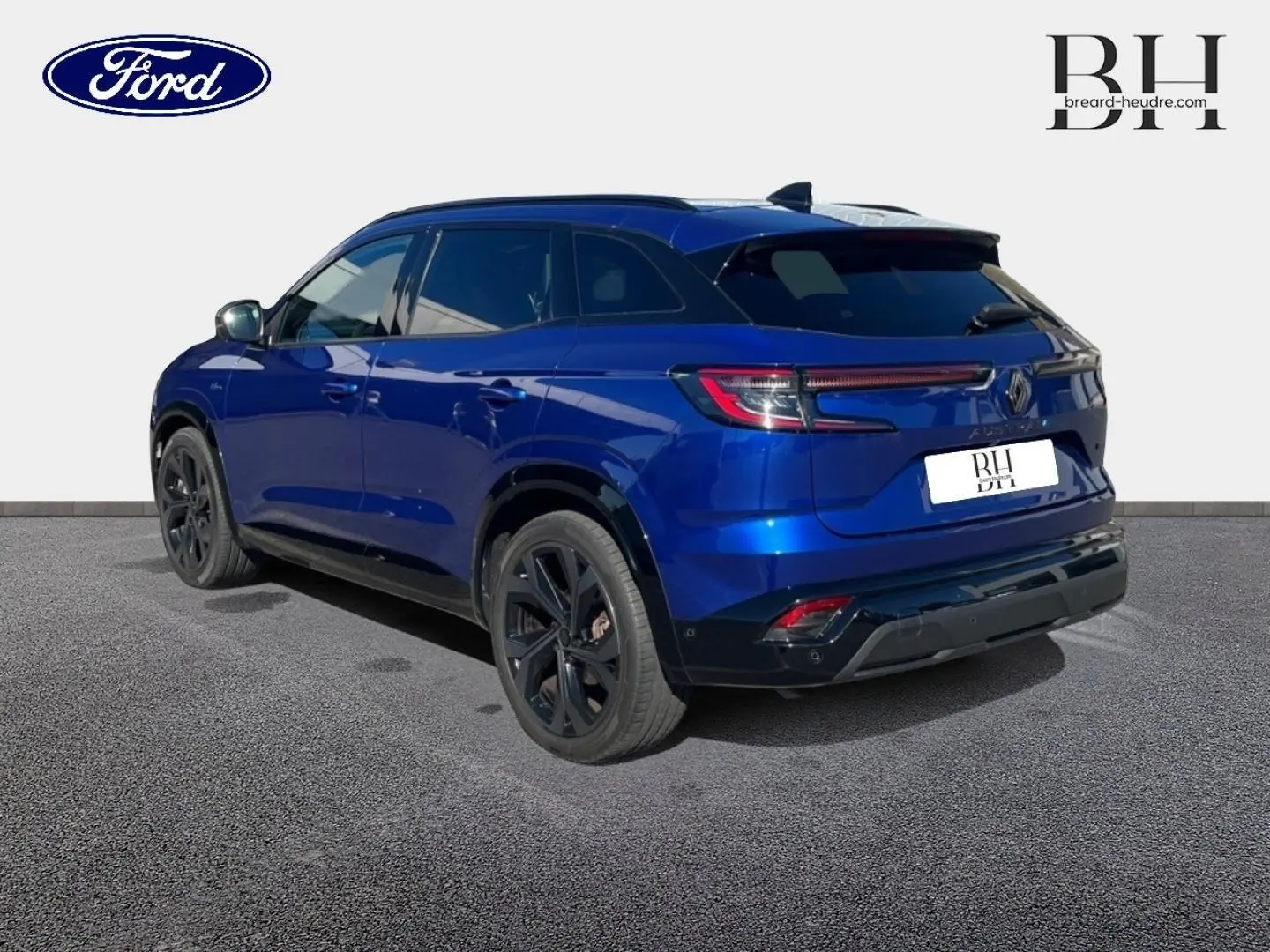 Vue 3/4 arrière droite d'un Renault Austral 2023 bleu Iron avec jantes noires et becquet arrière sportif.