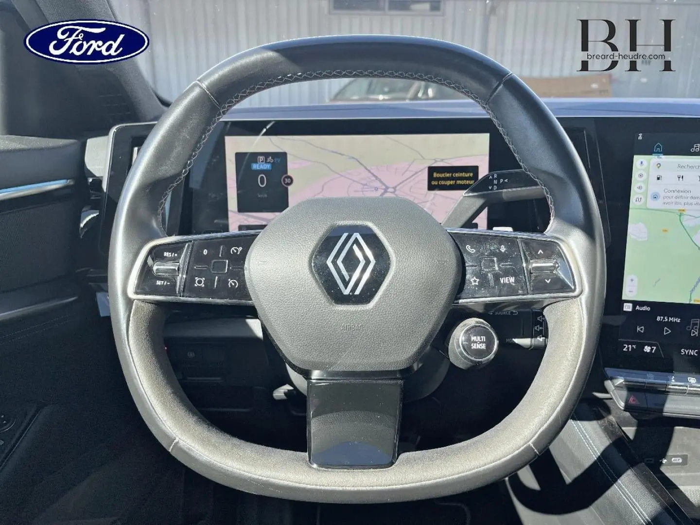 Vue rapprochée du volant cuir et alcantara avec logo Renault, écran tactile et commandes intégrées visibles.