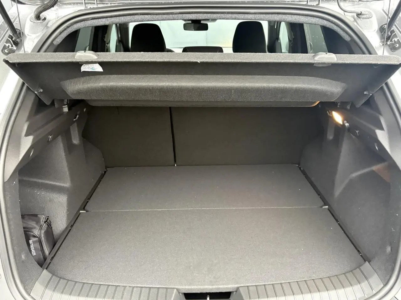 Coffre ouvert du Dacia Duster gris schiste, vue arrière montrant l'espace de chargement et la tablette cache-bagages.
