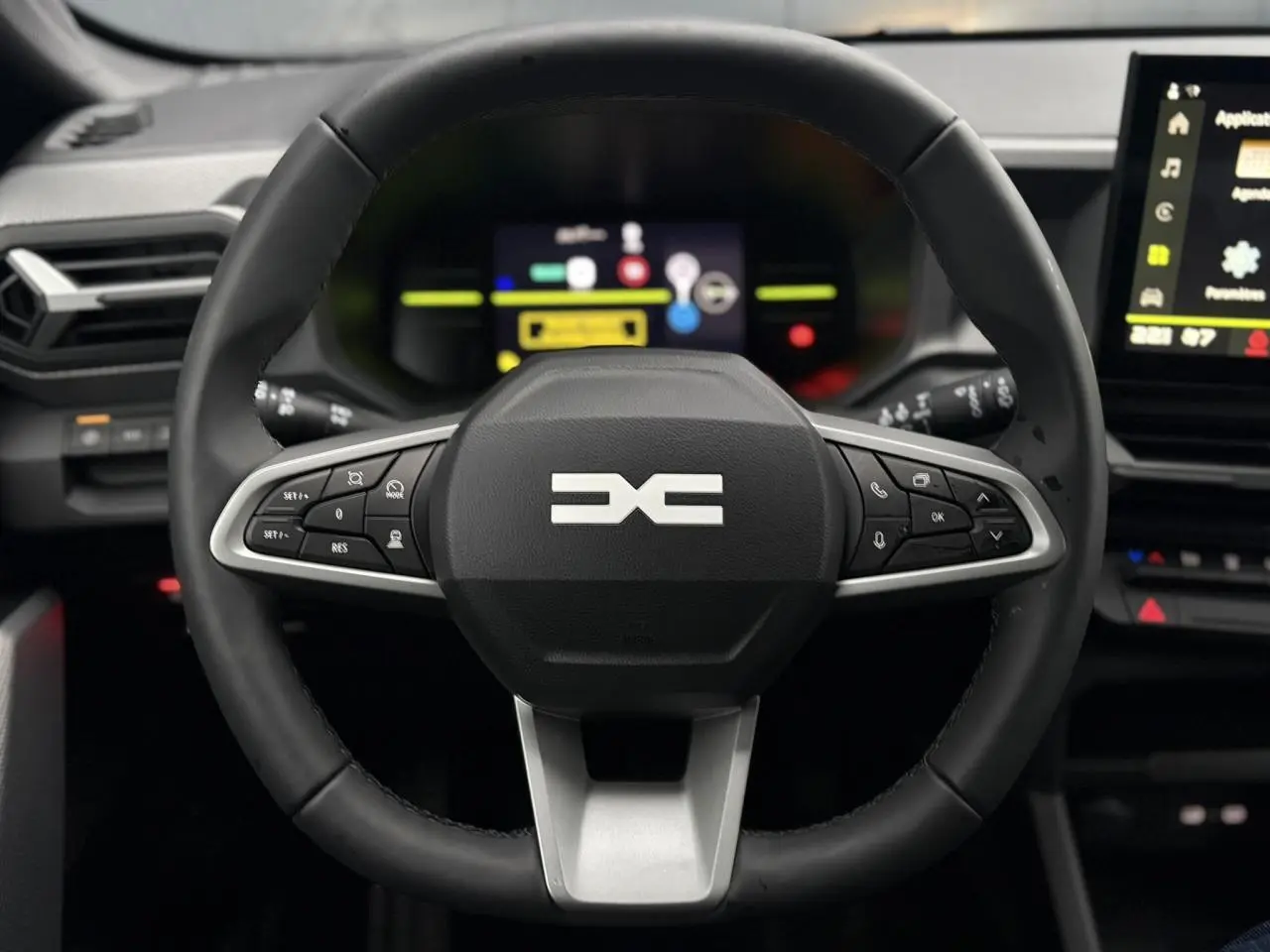 Vue frontale du volant noir du Dacia Duster 2026 avec commandes intégrées et tableau de bord digital en arrière-plan.