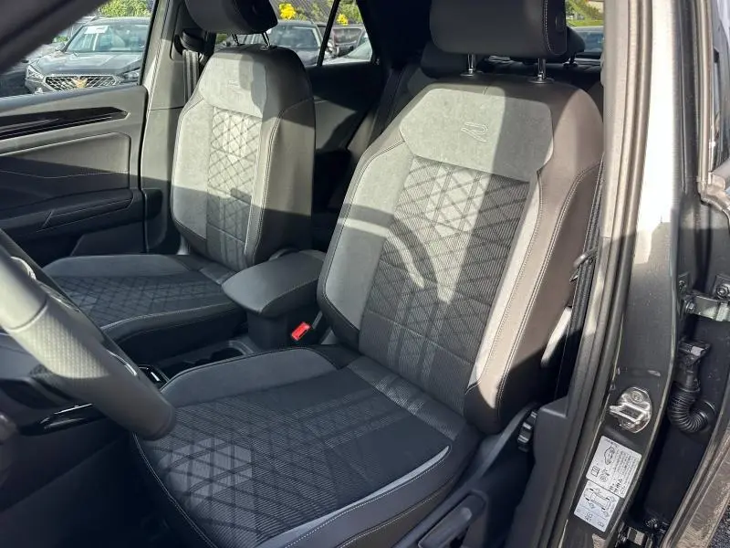 Vue intérieure côté conducteur du Volkswagen T-Roc gris 2025, sièges R-Line avec surpiqûres et logo brodé.