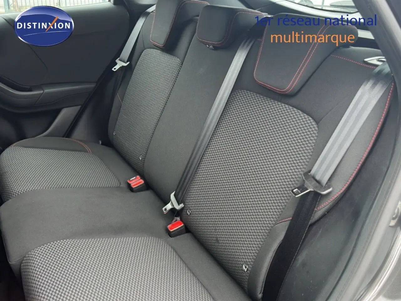 Vue intérieure sur les sièges arrière du Ford Puma gris magnétique 2024 avec surpiqûres rouges et ceintures grises.