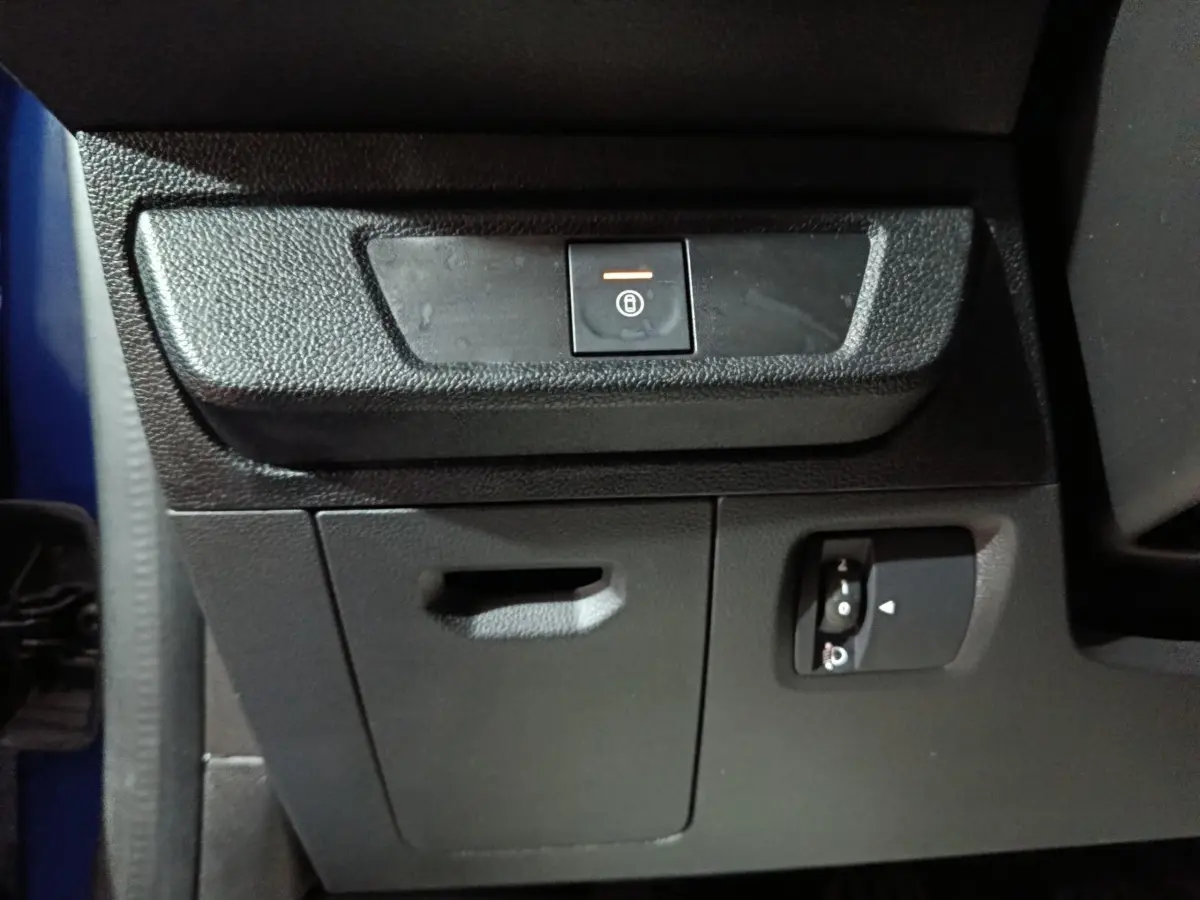 Détail intérieur montrant le bouton de condamnation centralisée sur la console côté conducteur d'une Dacia Sandero bleu 2024.