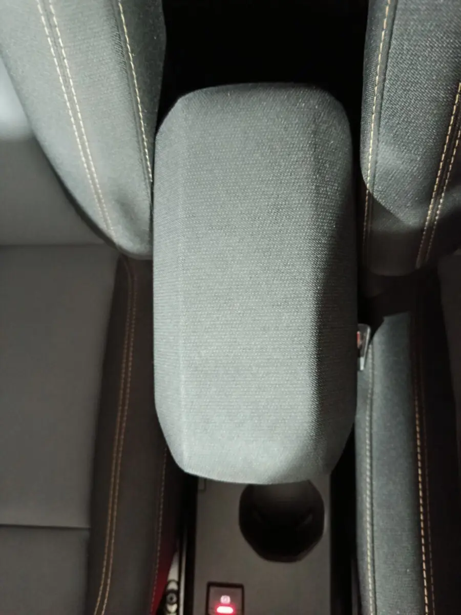 Vue plongeante sur l'accoudoir central en tissu gris entre les sièges avant de la Dacia Sandero 2024.