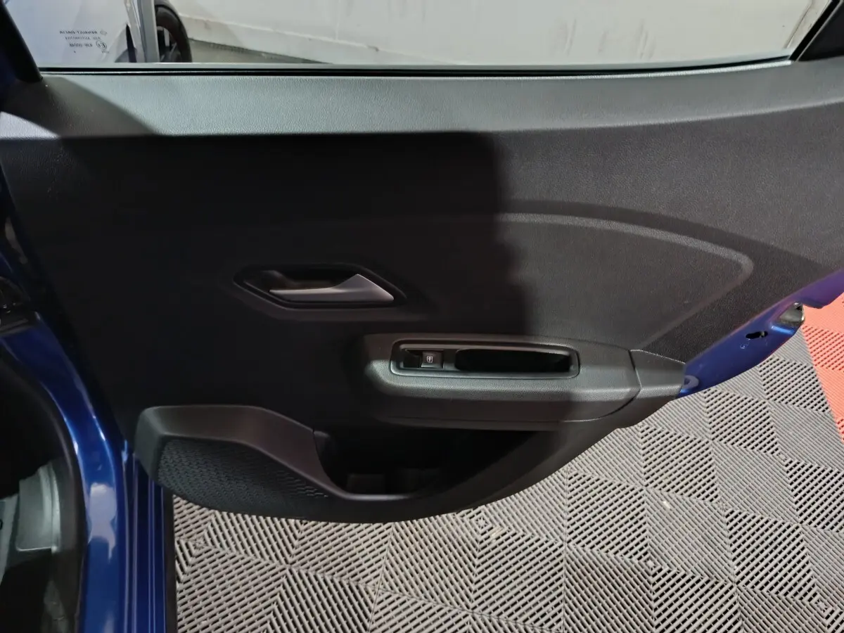 Vue rapprochée de la porte avant gauche bleu foncé de la Dacia Sandero Extreme+ avec commande de vitre électrique.