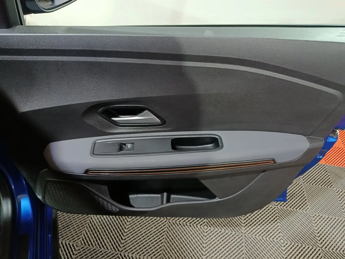 Vue intérieure du panneau de porte côté gauche bleu de la Dacia Sandero Extreme+ TCe 110 2024 avec commande de vitre électrique.