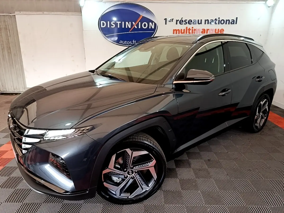 Vue 3/4 avant droite du Hyundai Tucson gris foncé 2022 avec jantes alliage et toit noir en intérieur showroom.