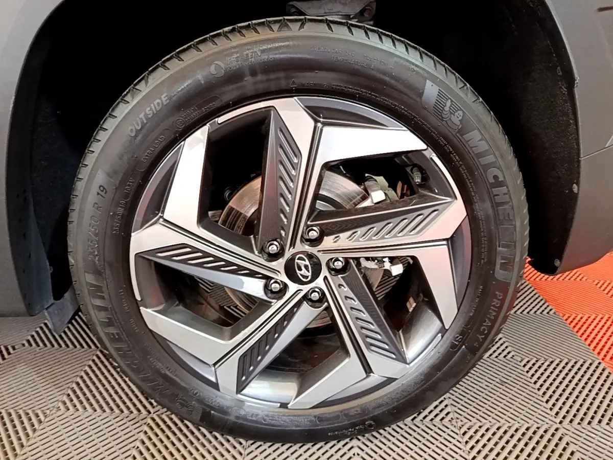 Gros plan sur la roue avant droite du Hyundai Tucson gris foncé, jante alliage au design moderne et pneu Michelin.