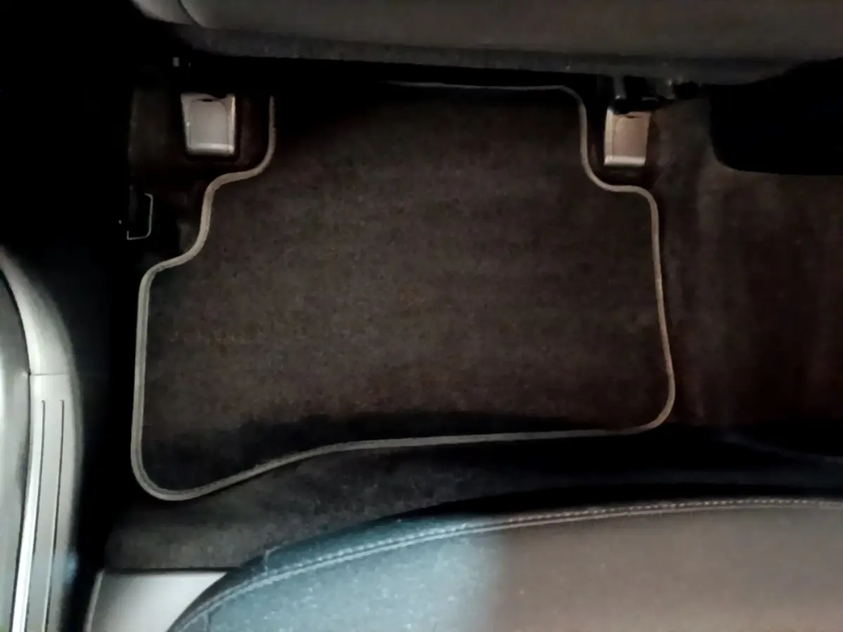 Vue plongeante sur le tapis de sol noir côté conducteur du Hyundai Tucson gris foncé 2022 hybride rechargeable.