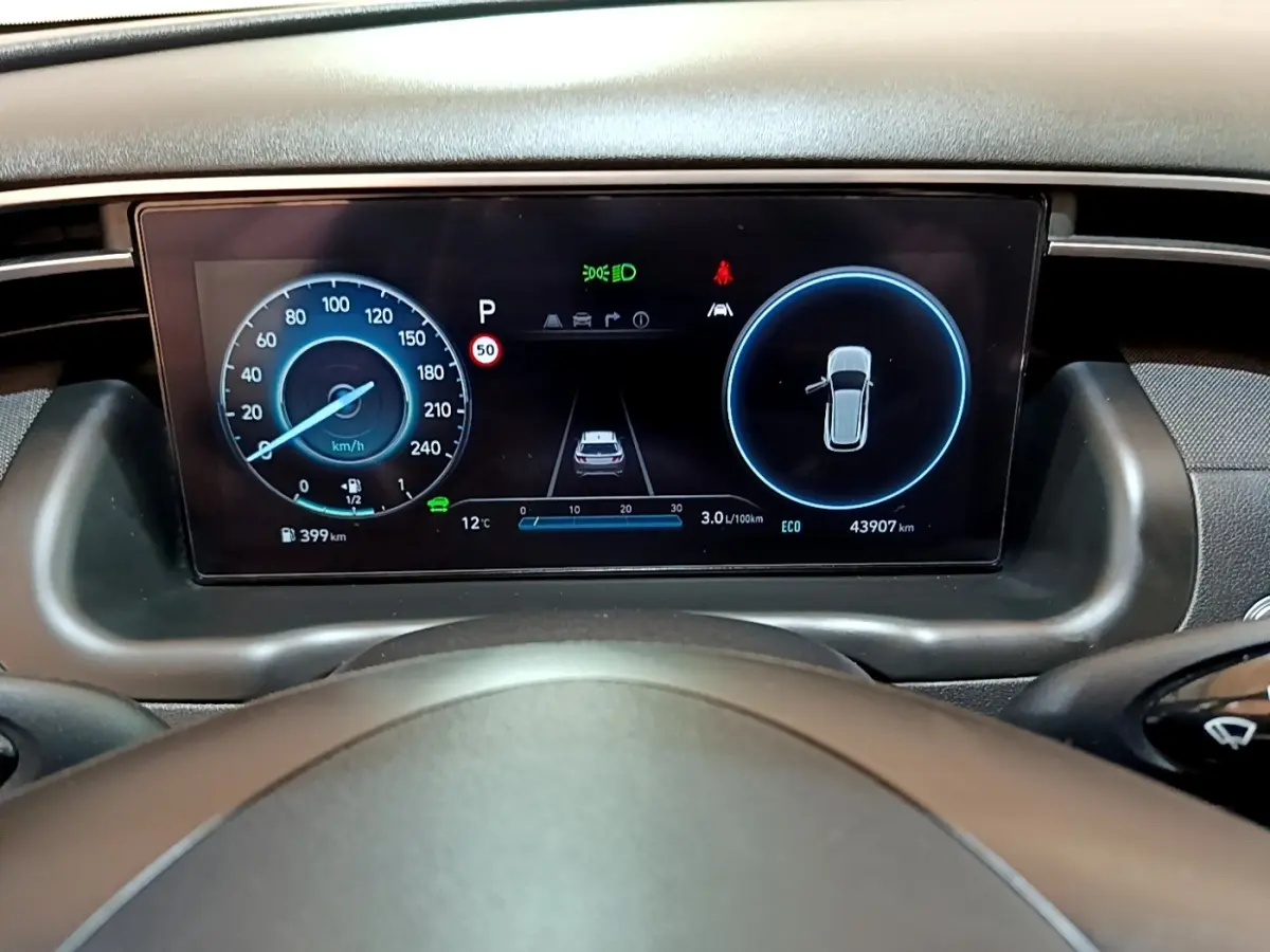 Tableau de bord numérique du Hyundai Tucson 2022, affichage vitesse et alertes, vue depuis le volant.
