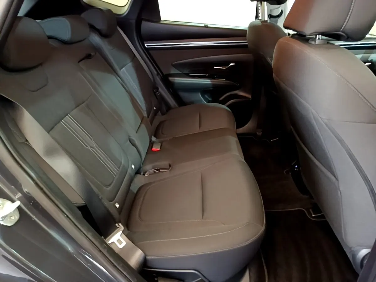 Vue intérieure côté gauche des sièges arrière gris foncé du Hyundai Tucson 2022, avec portières et ceintures visibles.