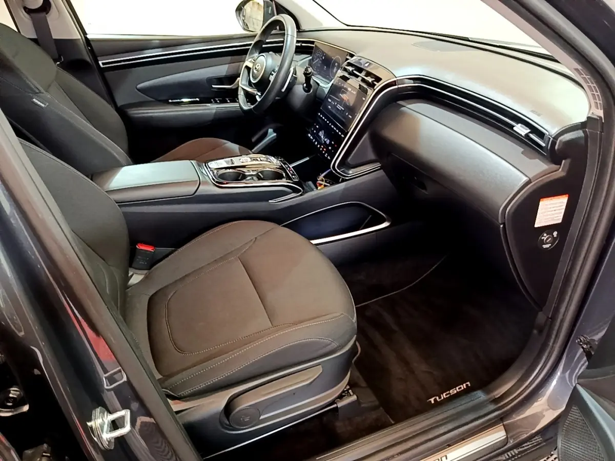 Intérieur du Hyundai Tucson gris foncé vu côté passager, avec tableau de bord moderne et sièges noirs.