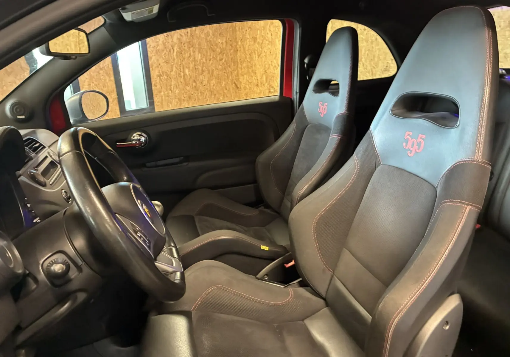 Vue intérieure côté conducteur de l'Abarth 500 Competizione 2016, sièges sport noirs avec logo 595 rouge et détails rouges.