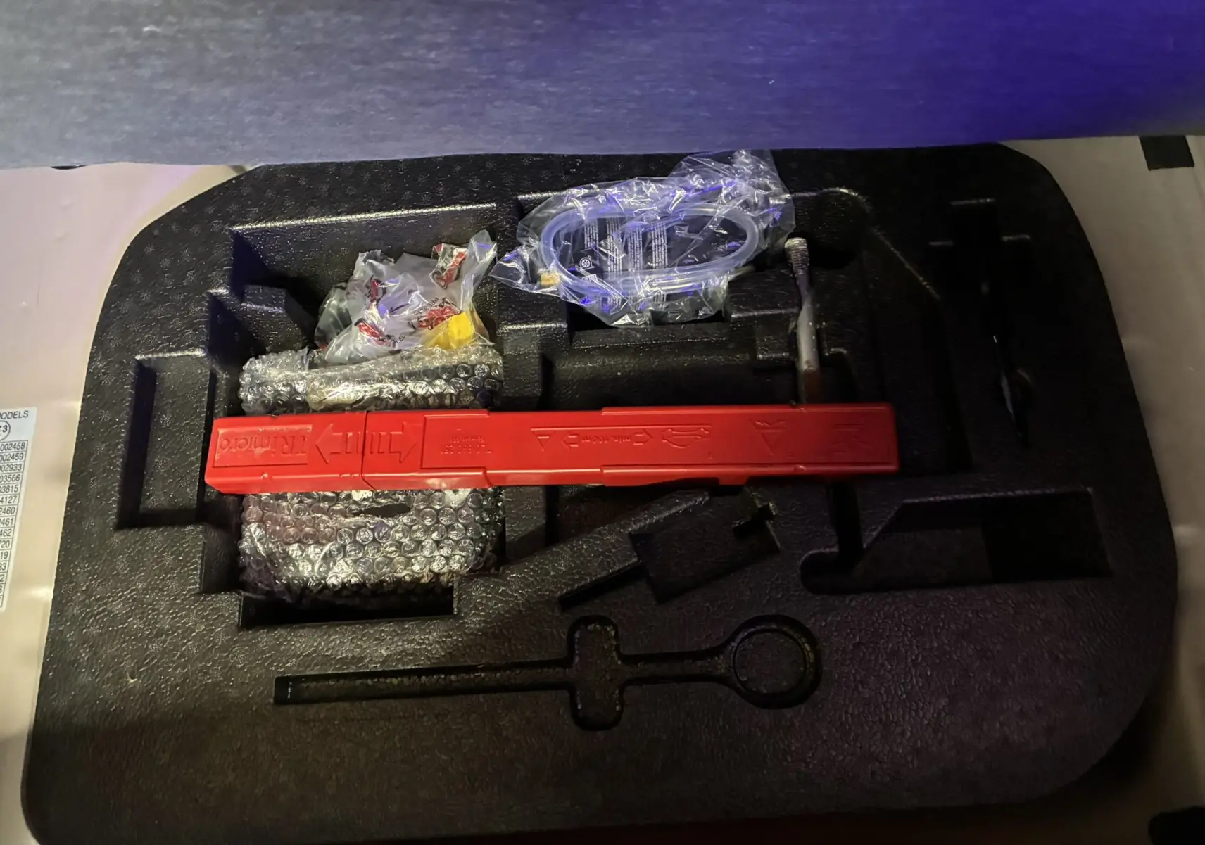 Coffret d’outils de bord avec triangle de signalisation rouge, présenté en vue plongeante sur mousse noire.