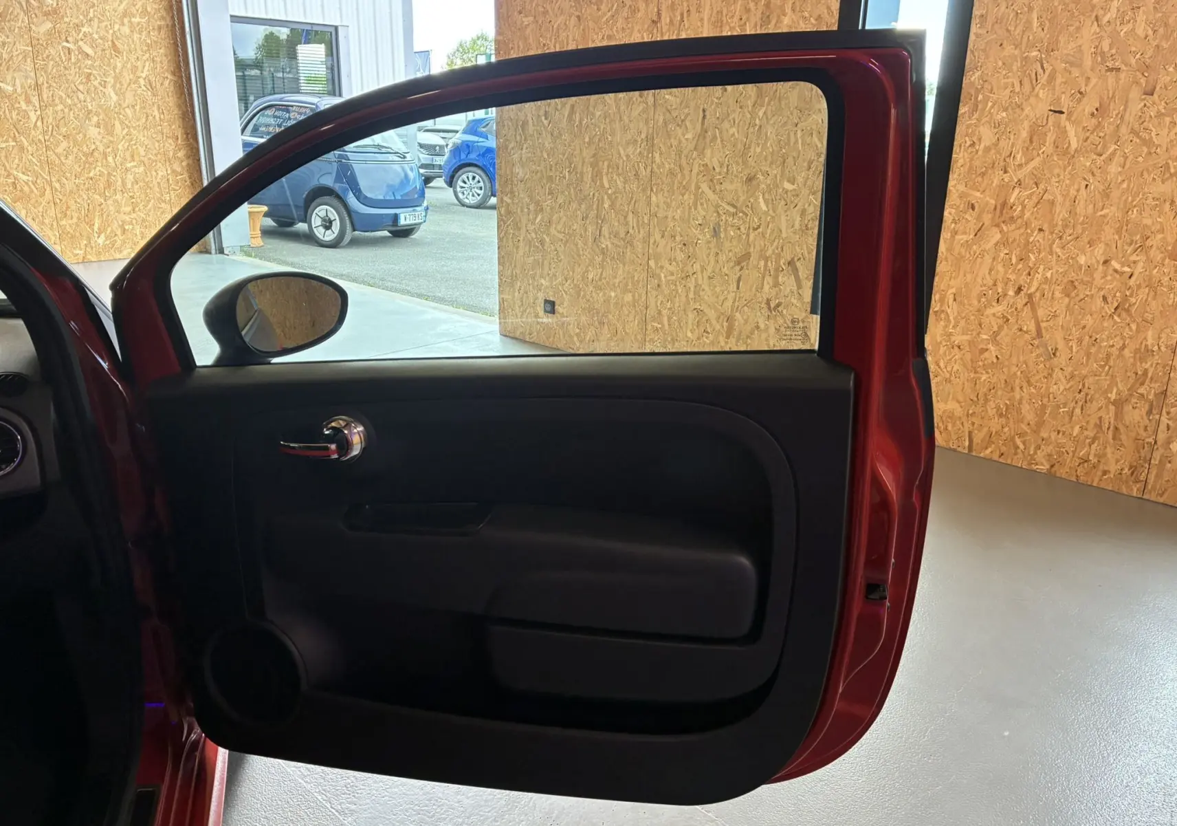 Vue intérieure de la porte avant gauche rouge de l'Abarth 500 Competizione 2016 avec poignée chromée et panneau noir.