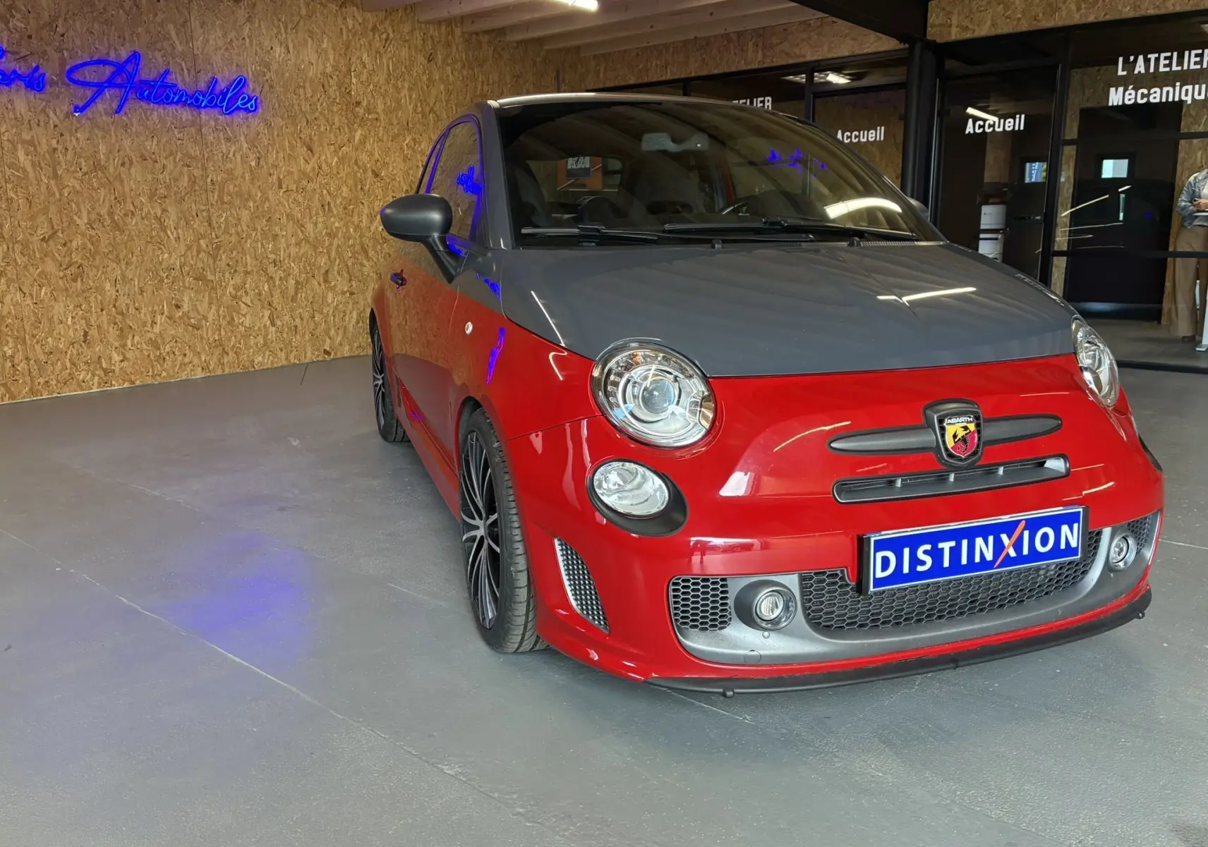 Vue 3/4 avant gauche d'une Abarth 500 Competizione 2016 rouge et gris avec jantes noires en concession.