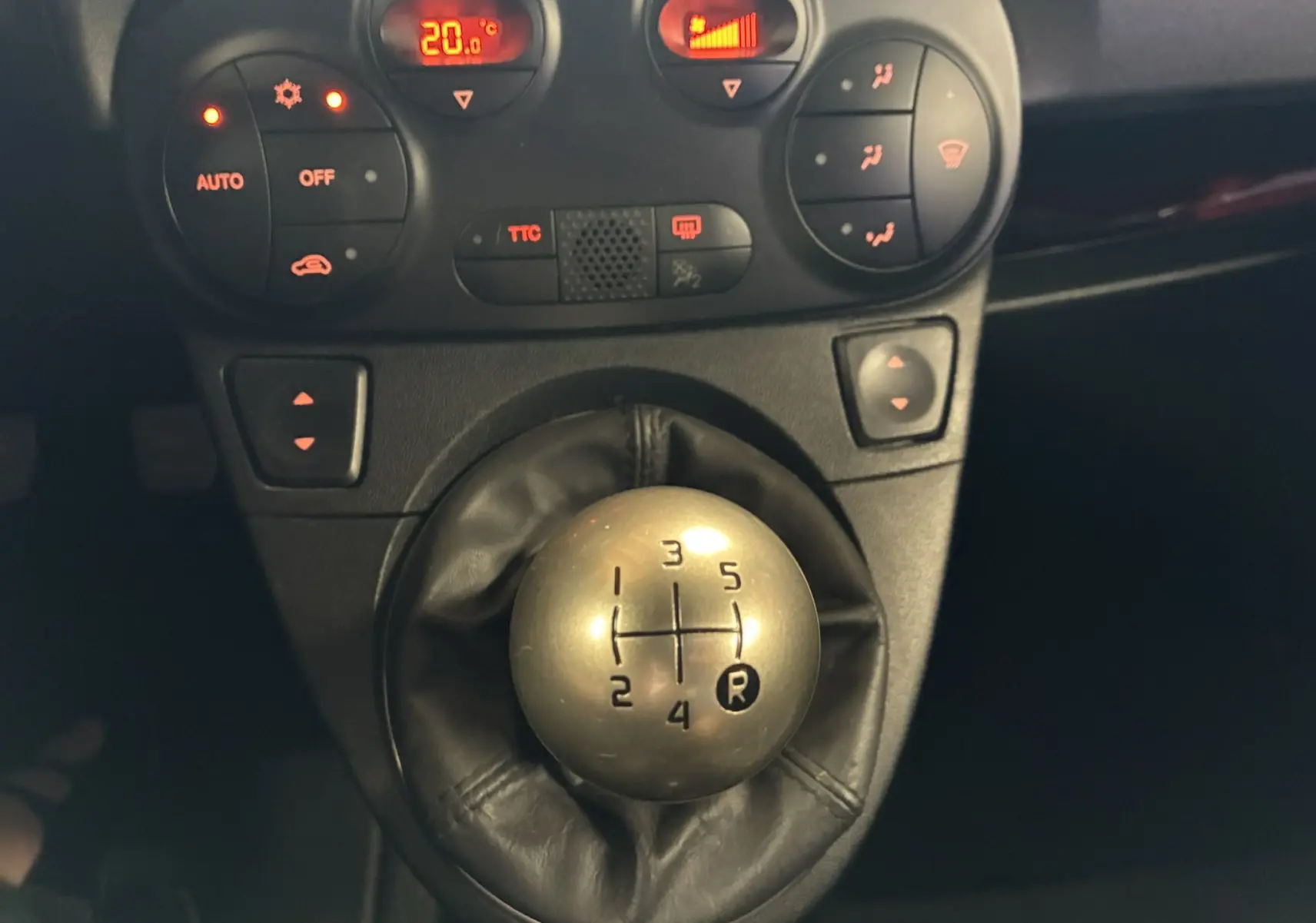 Gros plan sur le levier de vitesses manuel argenté et la console centrale avec commandes climatisation d’un Abarth 500 Competizione rouge et gris.