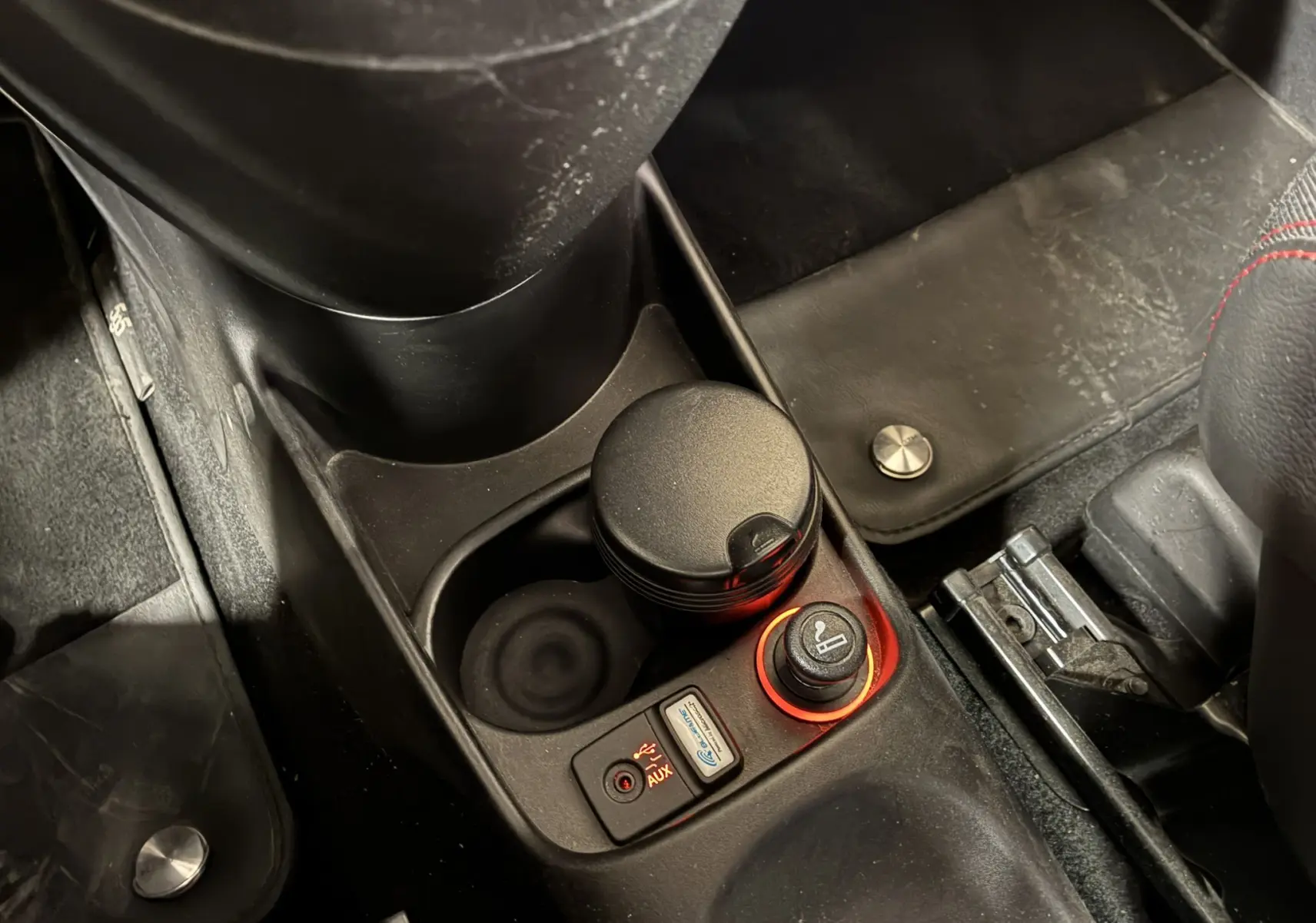 Gros plan sur la console centrale de l'Abarth 500 Competizione 2016, avec allume-cigare et prise auxiliaire éclairés.