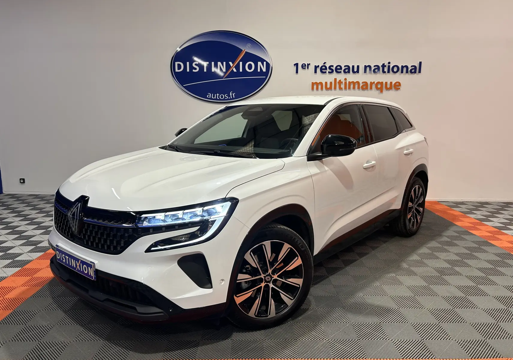 Renault Austral blanc nacré en 3/4 avant droit, avec phares LED allumés et jantes alliage distinctives.