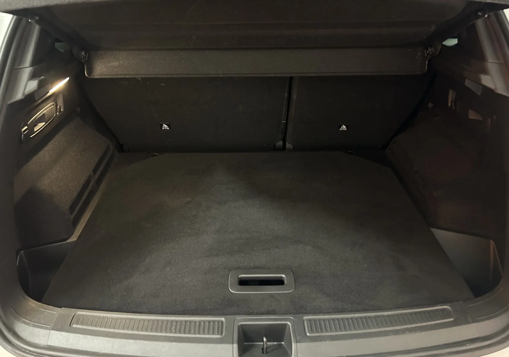 Coffre ouvert vu de l'arrière d'un Renault Austral blanc nacré, espace de chargement propre et vide avec hayon électrique.