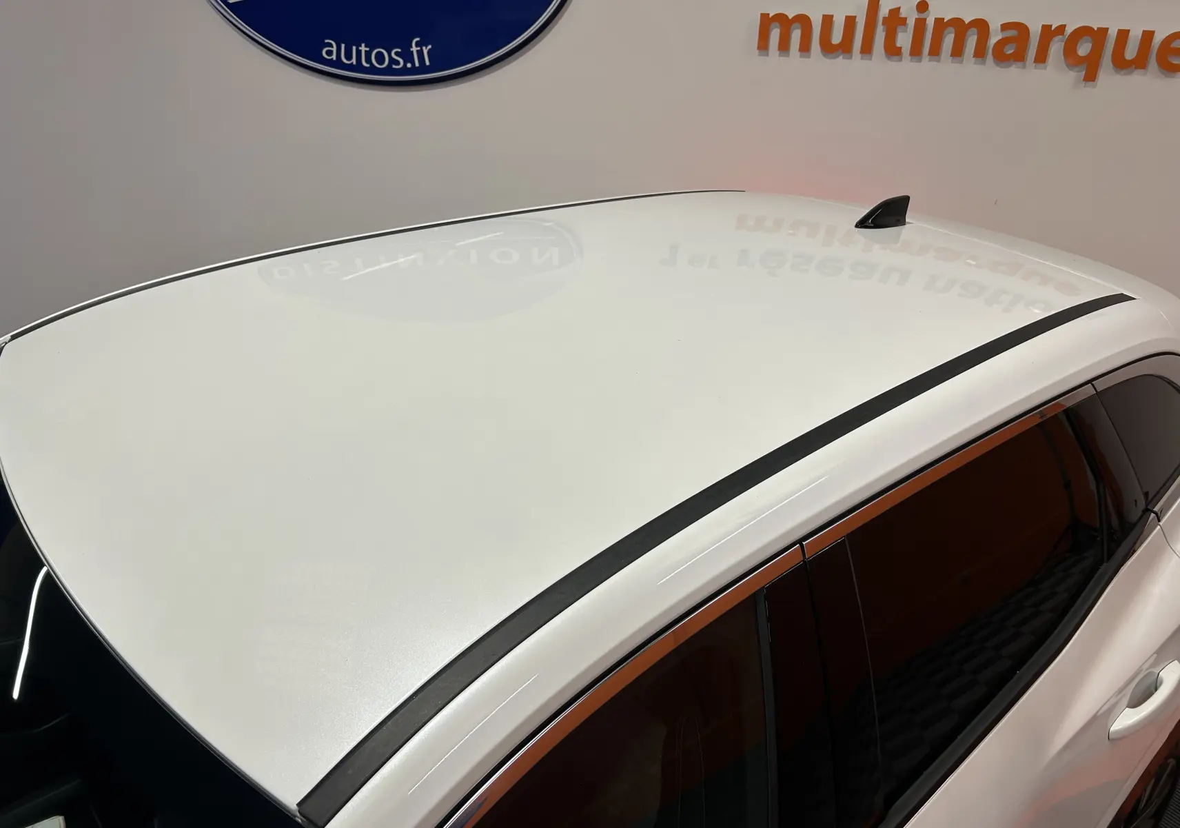 Vue en plongée du toit blanc nacré du Renault Austral E-Tech 2024 avec antenne requin et barres de toit noires.