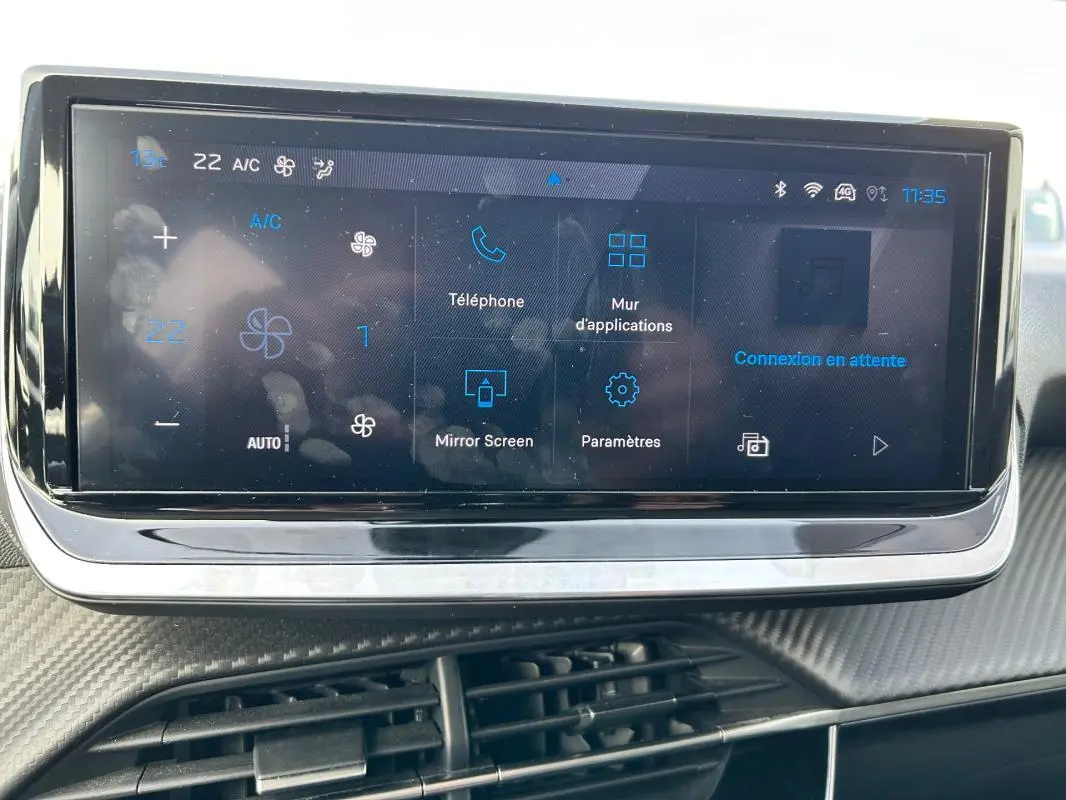 Écran tactile central de la Peugeot 208 Hybrid 110 gris, affichant les options de climatisation et connectivité.
