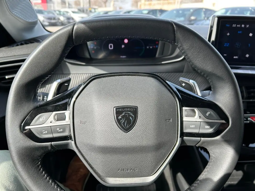 Vue rapprochée du volant cuir noir de la Peugeot 208 Hybrid 110 e-DCS6 Allure 2024 gris, avec commandes intégrées.