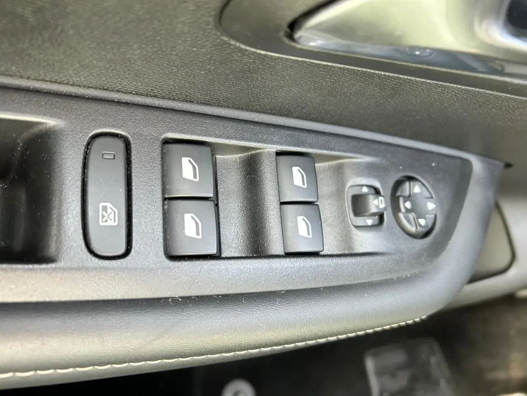 Gros plan sur les commandes des vitres et rétroviseurs côté conducteur de la Peugeot 208 Hybrid 110 e-DCS6 Allure 2024.