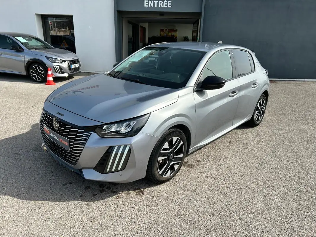 Peugeot 208 Hybrid gris vue 3/4 avant droit, avec calandre distinctive et feux LED verticaux marquants.