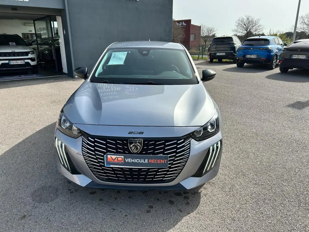 Peugeot 208 Hybrid 110 e-DCS6 Allure gris vue de face, avec calandre noire et feux diurnes LED verticaux.
