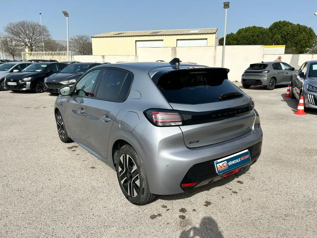 Peugeot 208 Hybrid gris vue 3/4 arrière droit, avec feux arrière distinctifs et jantes noires bicolores.