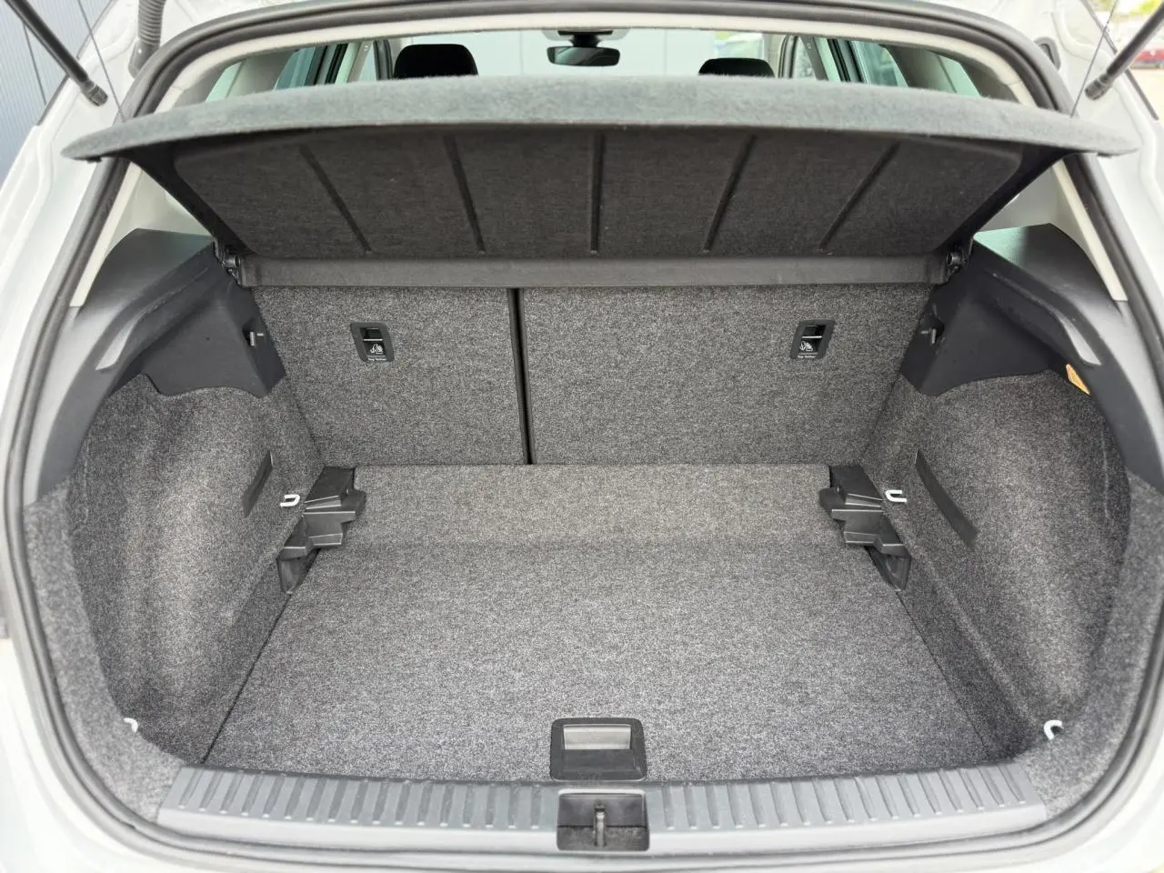 Coffre ouvert vu de l'arrière d'un SEAT Arona blanc, montrant un espace de rangement propre et bien agencé.