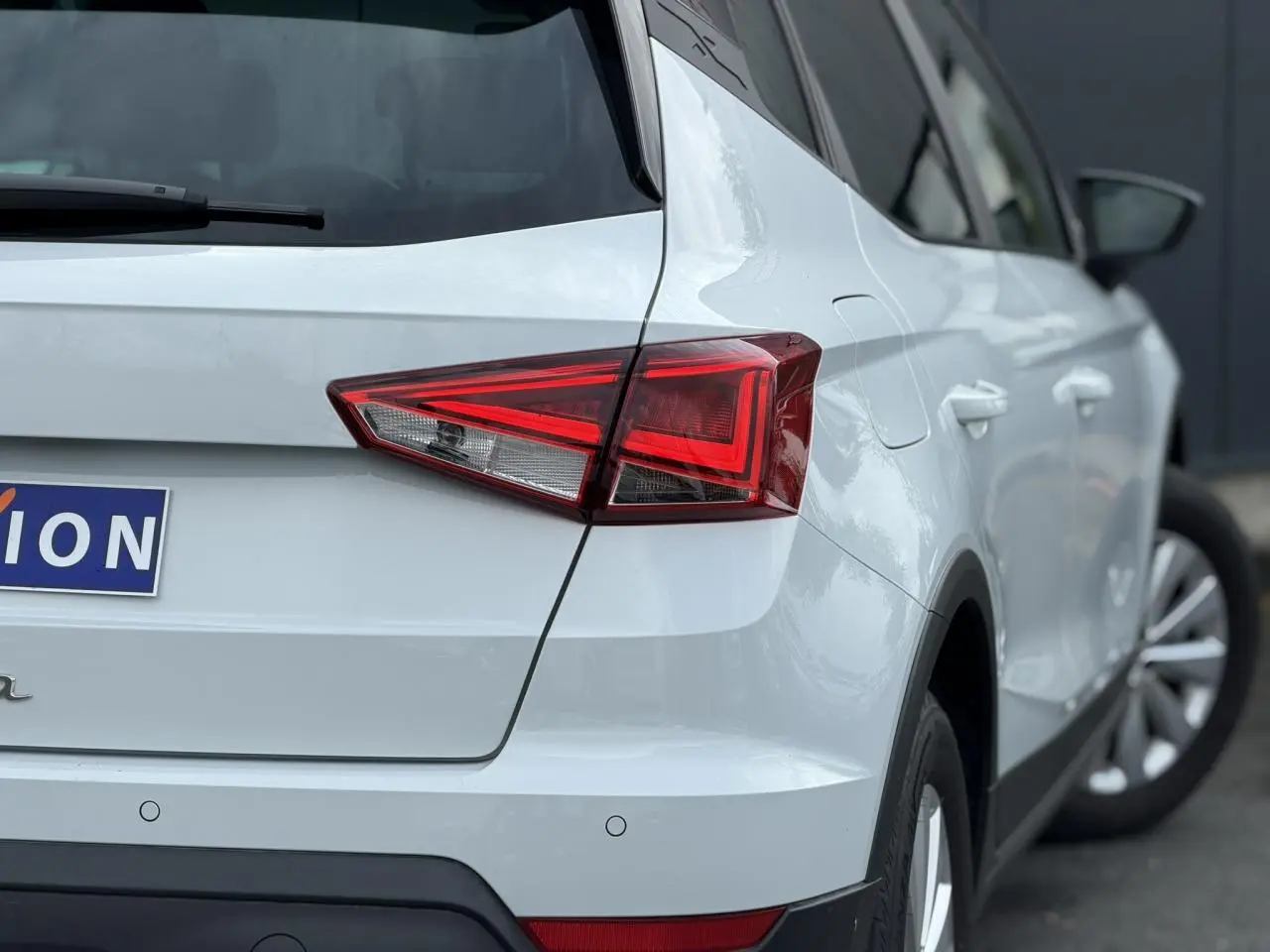 Vue arrière côté gauche d'un SEAT Arona blanc alpin avec feux arrière LED et jantes alliage 16 pouces.