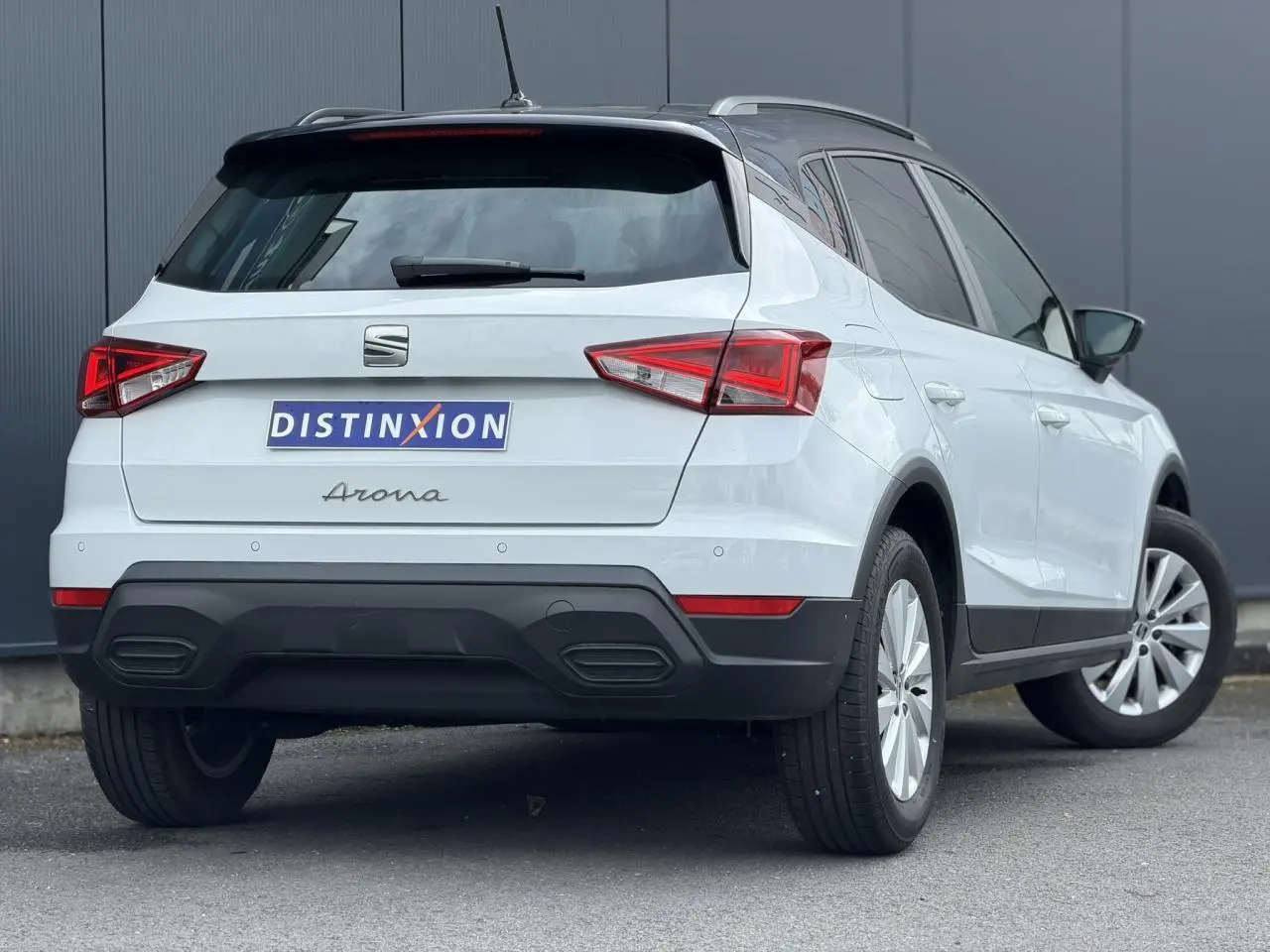 Vue 3/4 arrière droite d'un SEAT Arona blanc alpin avec toit noir et jantes alliage 16 pouces.